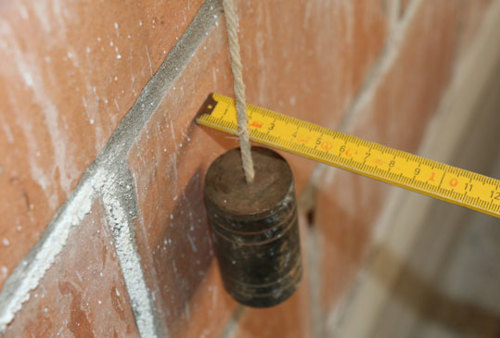 L’aplomb (ou la verticalité) d’un mur se mesure au moyen d’un fil à plomb.