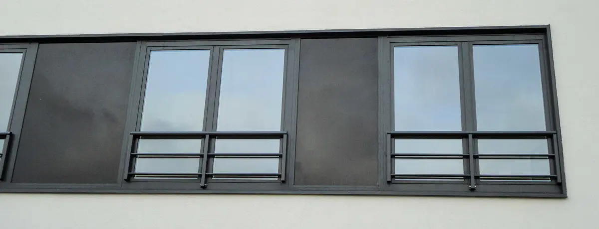 Geveldetail met een rij ramen boven een horizontaal gevelelement. Détail de façade avec une rangée de fenêtres au-dessus d’un élément horizontal.