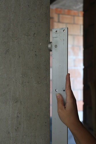 Mesure de la rectitude des bords d’un mur en béton à l’aide d'une latte rigide de 2 m. Cette photo présente un détail du positionnement de la latte de contrôle de 2 m contre le bord à mesurer.