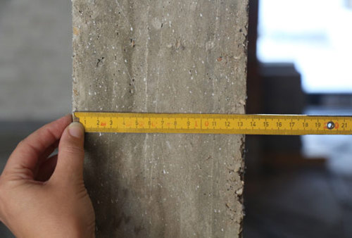 Meten van de dikte van een betonnen wand met behulp van een vouwmeter.