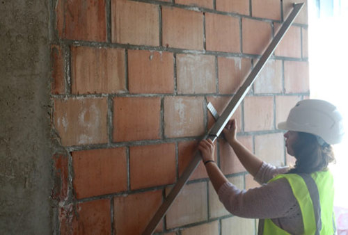 Mesure de la planéité d’un mur en maçonnerie de briques sous une latte rigide de 2 m.